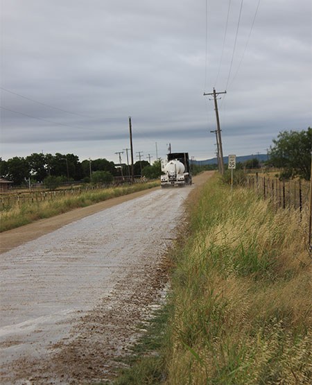 Long road leading into the horizon with an 18 wheeler driving on it.