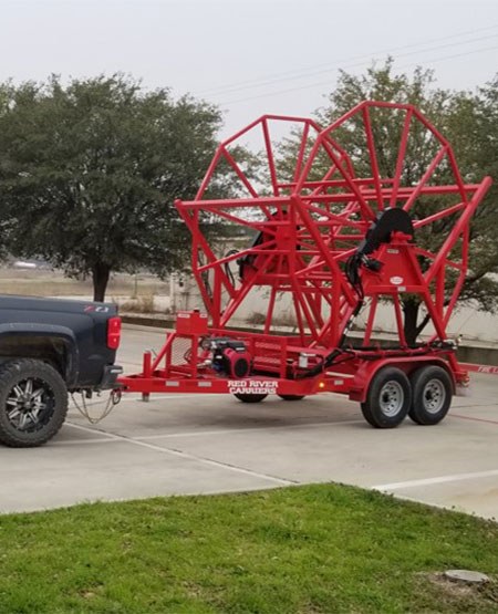 Large red poly service equipment being towed by a blue Chevy truck.