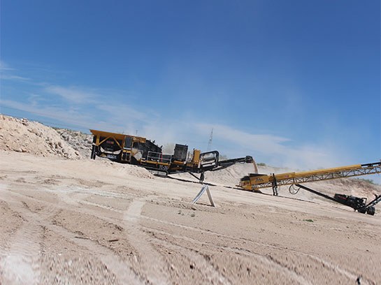 Very large crusher service equipment in a white dirt field.