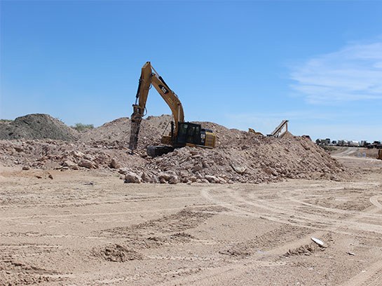 Heavy machine operate drilling equipment working in a white dirt field.