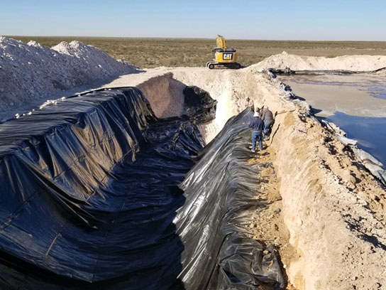 Large pit construction with black tarp covering the pit.