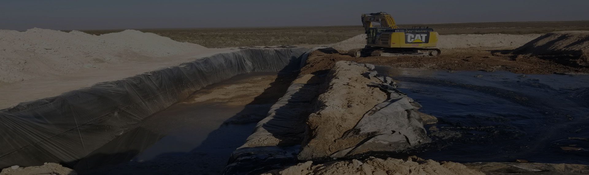 Faded background of a large trench filled with water next to white gravel.