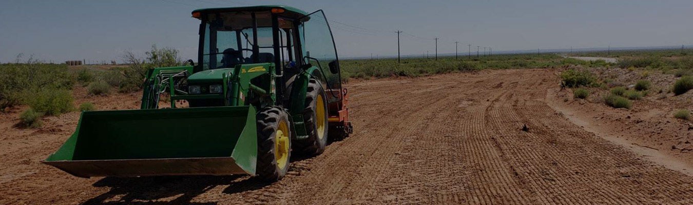 Faded background of a large green tractor working in a dirt field.