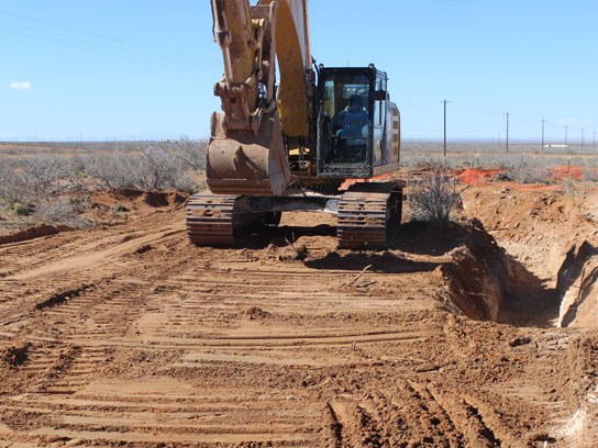 Large yellow caterpillar hard at work digging a pit of dirt.