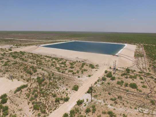 Large pit filled with water with a dirt road leading to it.