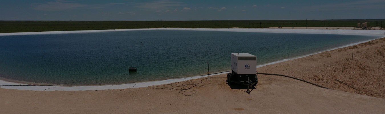 Large pit filled with water in the middle of a dirt field.