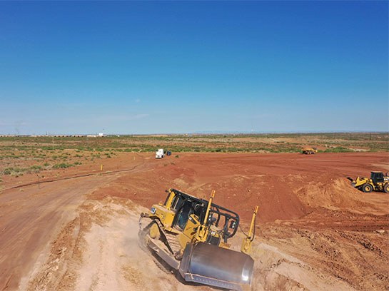 Yellow caterpillar sitting in a large open dirt field.