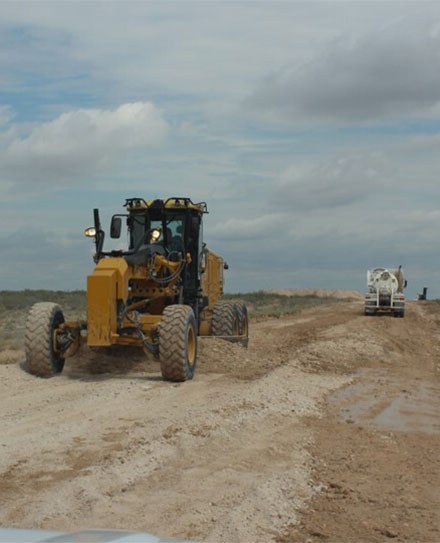 Large yellow heavy machinery hard at work in a dirt field.