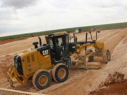 A large yellow tractor working hard in a dirt field.